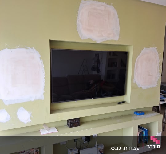 קיר עם תיקוני גבס סביב טלוויזיה